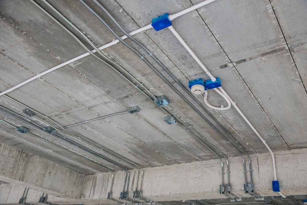 Conduit pipes and junction boxes fixed to a concrete ceiling