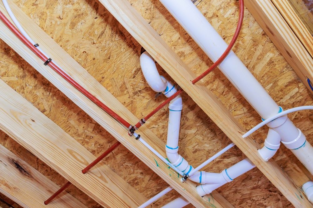 White PVC plumbing pipes running between timber floor joists