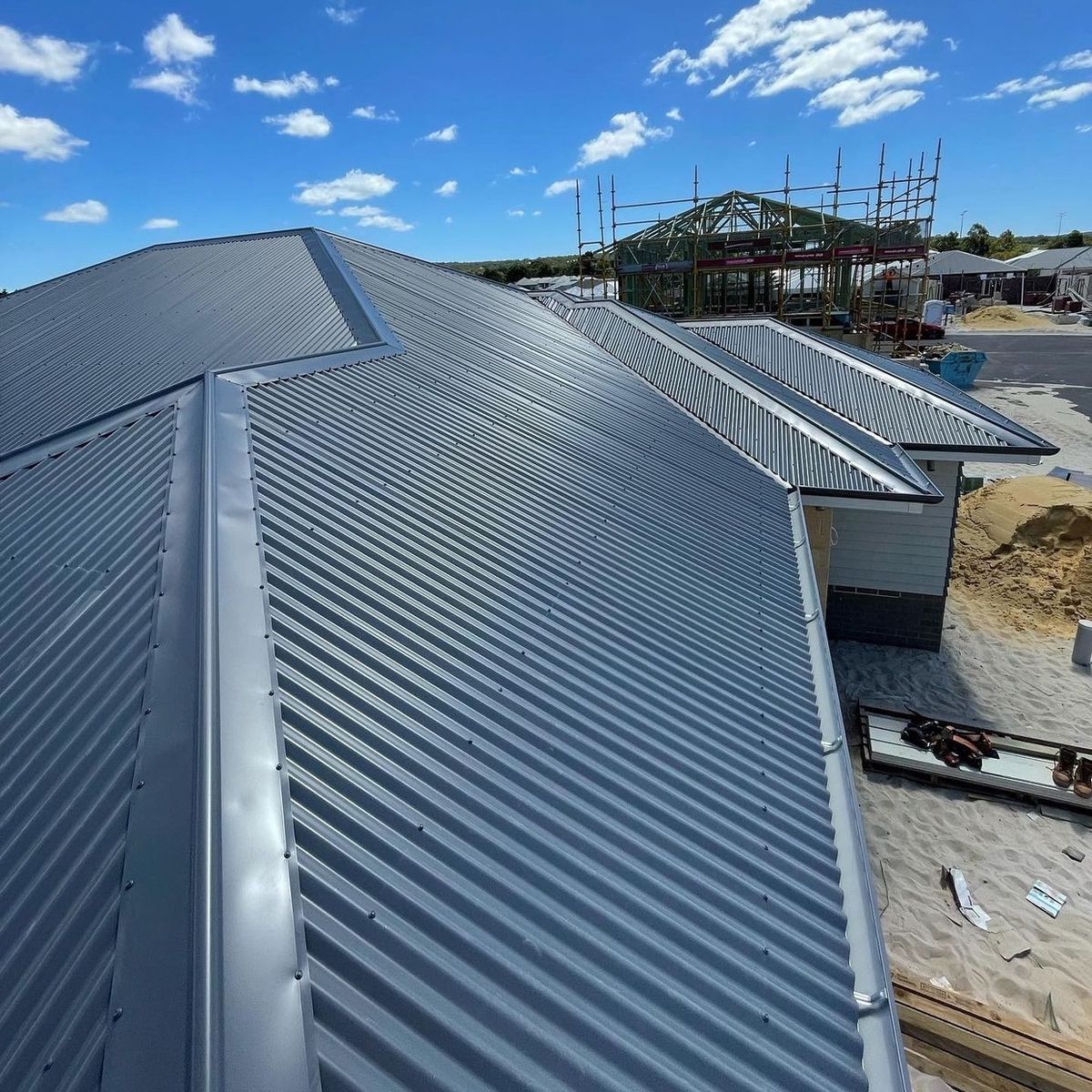 Grey corrugated steel roof on a new house with more houses being built behind