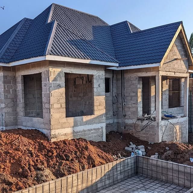 New block house with a blue tile-profile steel roof under construction