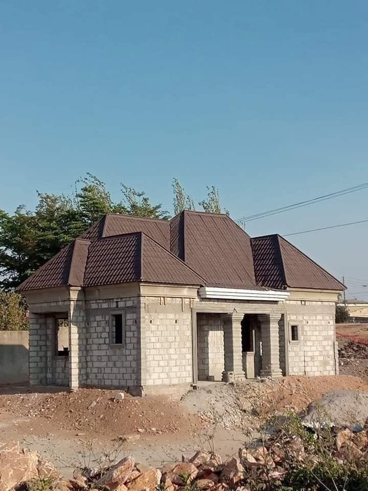 Brown tile-profile steel roof with several hips on a new block house